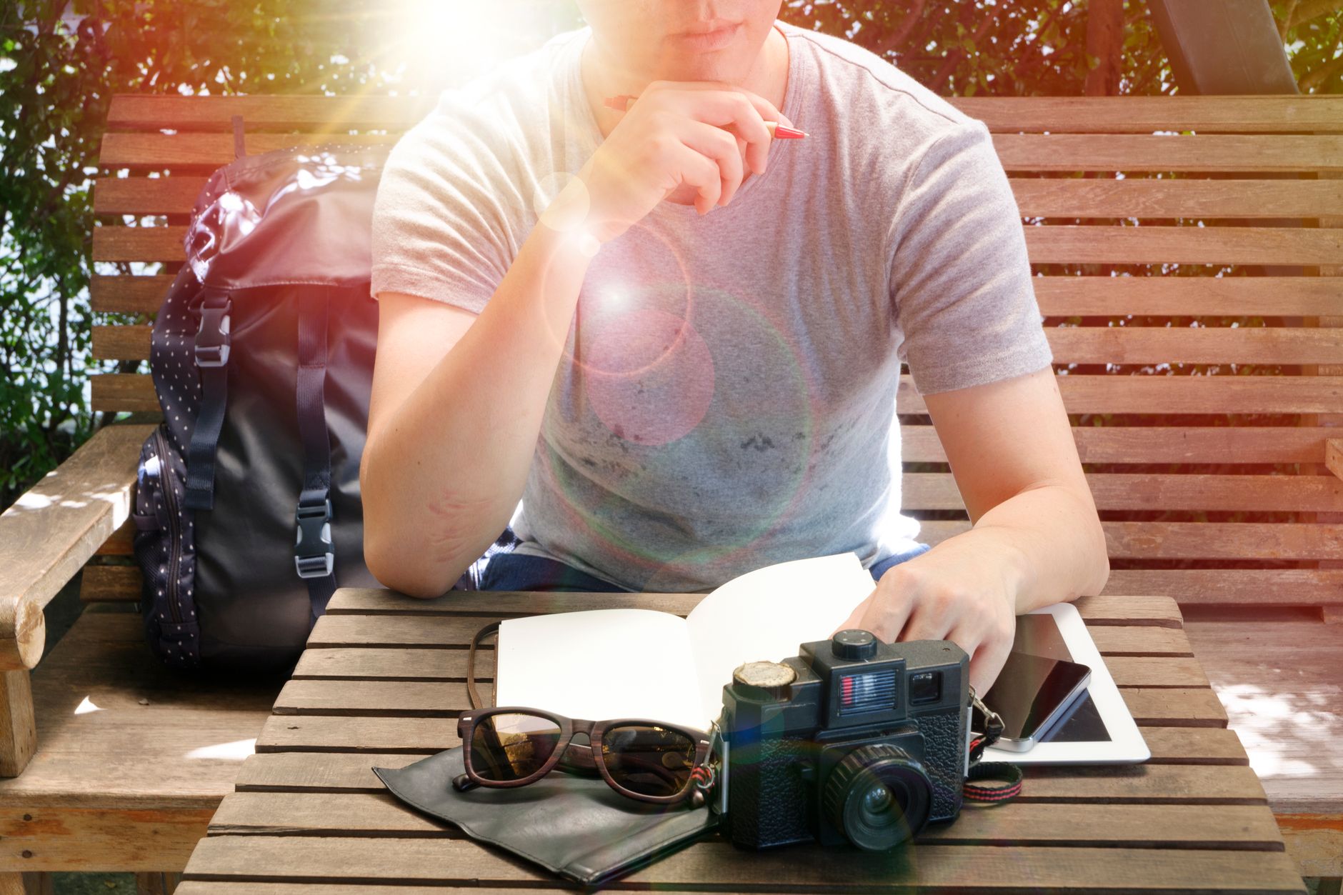 Travel journal and old camera resting on rustic wooden table